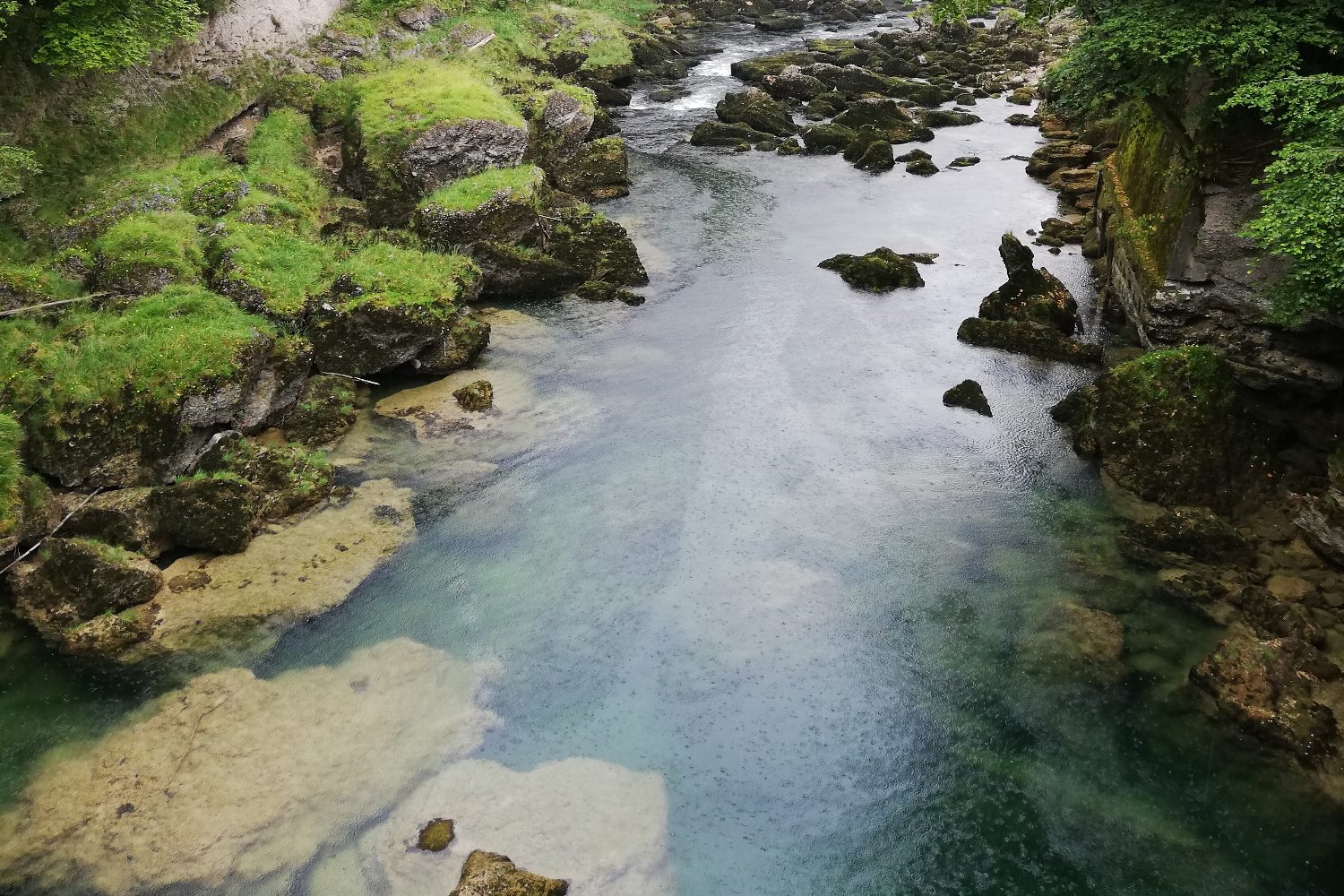 Klarer Gebirgsfluss zwischen bemoosten Felsen an den Traunfällen