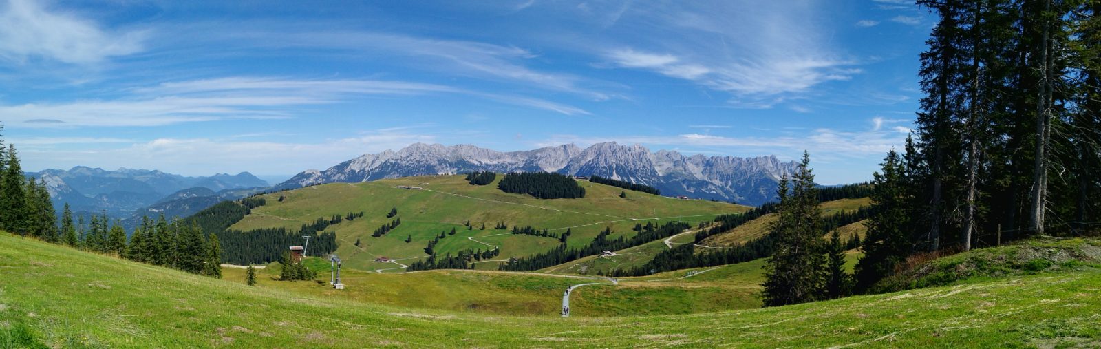 Weites Almpanorama mit Bergkette unter blauem Himmel
